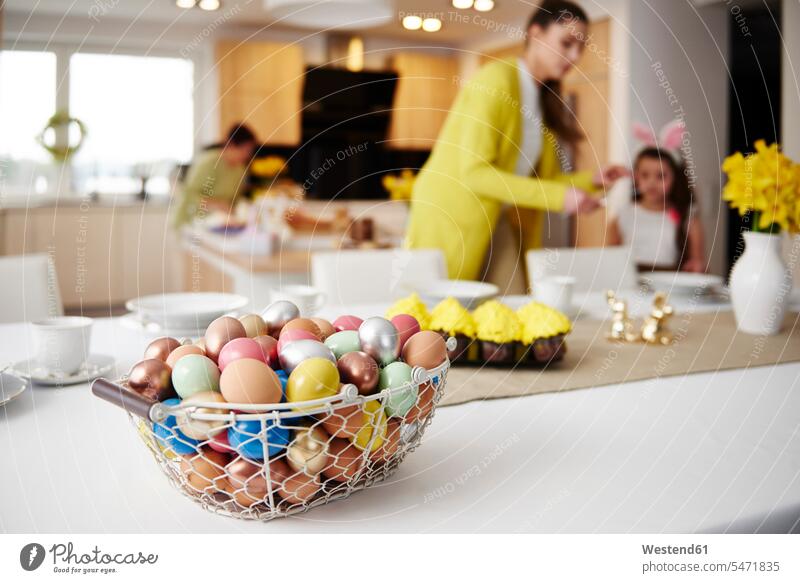 Easter eggs in basket on table at home with mother and daughter in background together Egg Eggs daughters family families baskets mommy mothers ma mummy mama