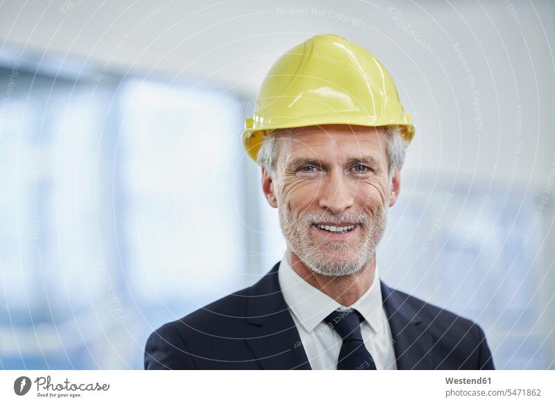 Happy mature male manager wearing yellow hardhat in factory color image colour image indoors indoor shot indoor shots interior interior view Interiors day