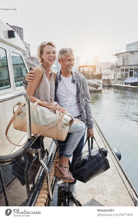 Older man and young woman standing with travelling bags on jetty next to yacht Yacht Yachts traveling bags jetties couple twosomes partnership couples vessel