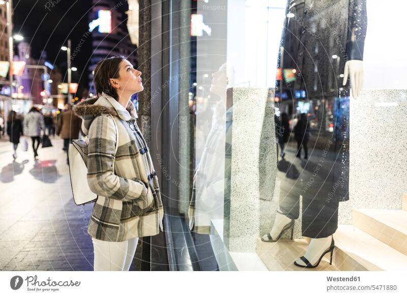 Spain, Madrid, young woman in the city at night next to Gran Via looking at a window shop females women town cities towns by night nite night photography Adults