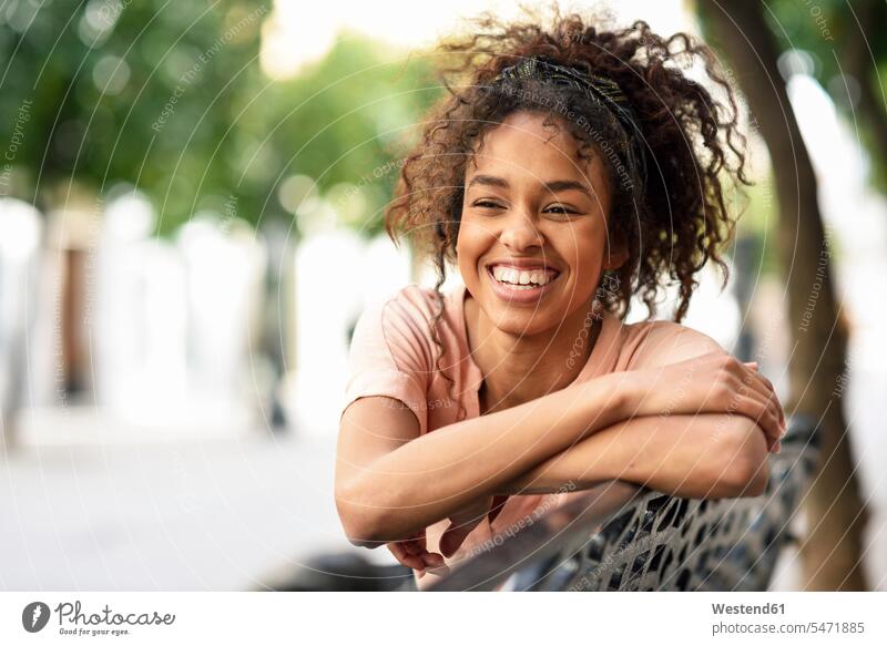 Portrait of happy young woman sitting on a bench happiness benches Seated females women portrait portraits Adults grown-ups grownups adult people persons
