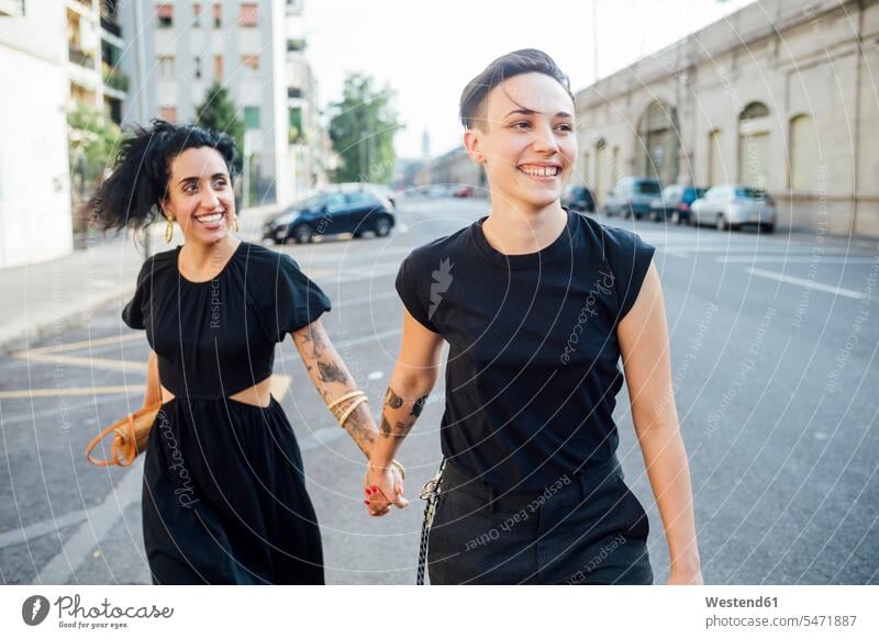 Smiling lesbian couple walking in city color image colour image outdoors location shots outdoor shot outdoor shots day daylight shot daylight shots day shots