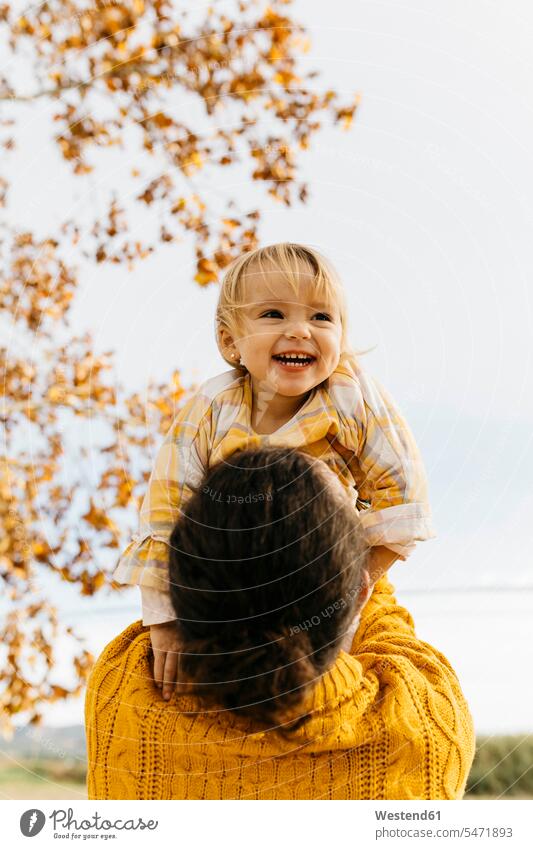 Father holding his daughter on a morning day in the park in autumn daughters in the morning autumnal autumnally laughing Laughter parks Joy enjoyment pleasure