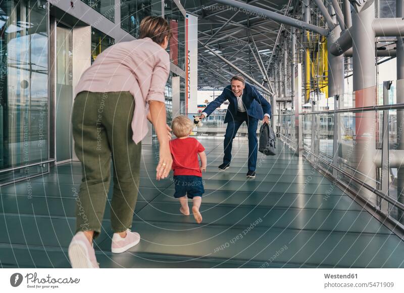 Happy child running into arms of travelling businessman at the airport Businessman Business man Businessmen Business men family families father pa fathers daddy