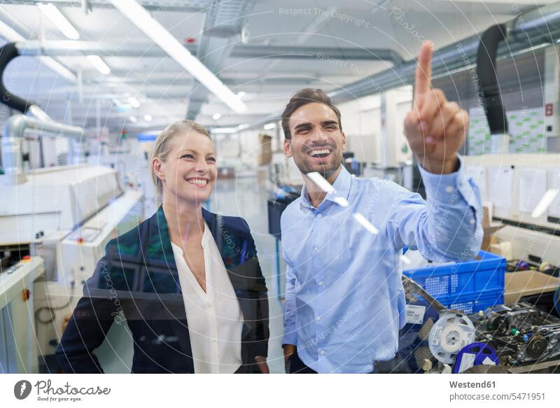 Happy young male technician pointing at graphical interface on glass in factory color image colour image indoors indoor shot indoor shots interior interior view