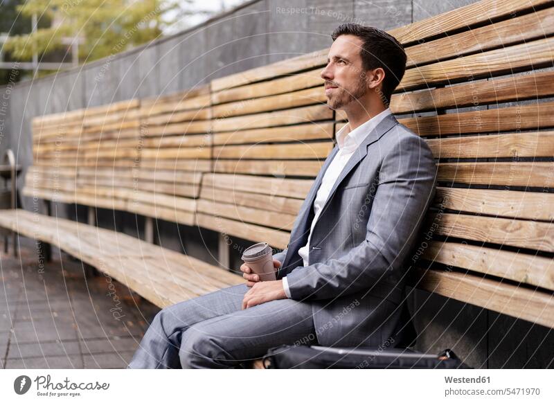 Relaxed businessman sitting on wooden bench in the city business life business world business person businesspeople Business man Business men Businessmen