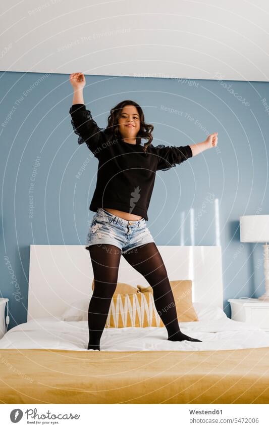 Cheerful young woman with down syndrome dancing on bed at home caucasian caucasian appearance caucasian ethnicity european White - Caucasian caucasians