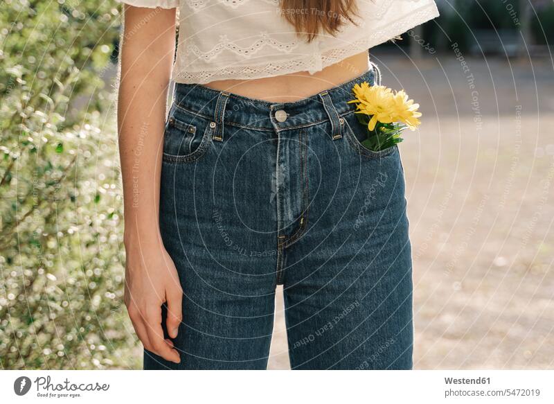 Woman standing with yellow flower in pocket color image colour image outdoors location shots outdoor shot outdoor shots day daylight shot daylight shots