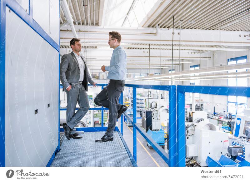 Two businessmen talking on upper floor in a factory Occupation Work job jobs profession professional occupation business life business world business person