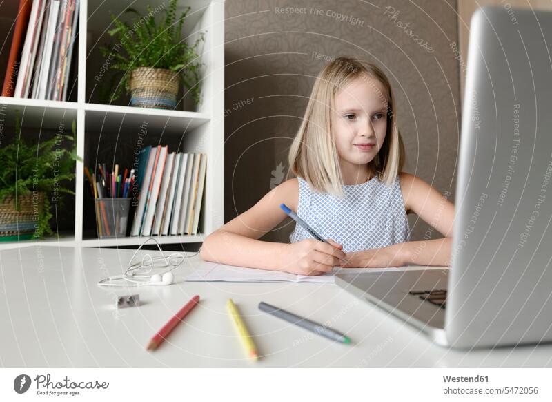 Girl sitting at table at home doing homework and using laptop Tables pencil pencils pens computers Laptop Computer Laptop Computers laptops notebook learn smile
