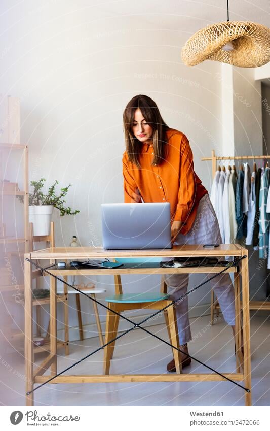 Female fashion designer working at home at desk with laptop human human being human beings humans person persons caucasian appearance caucasian ethnicity