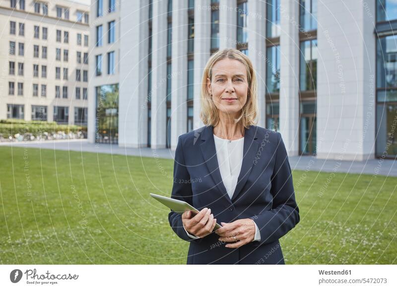 Portrait of confident businesswoman with tablet standing on lawn in the city Occupation Work job jobs profession professional occupation business life