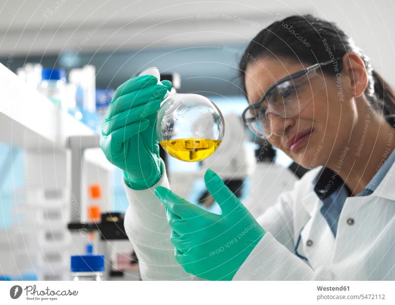Biotech Research, Scientist swirling a chemical formula in a laboratory flask during a experiment liquids sciences scientific natural sciences controlling