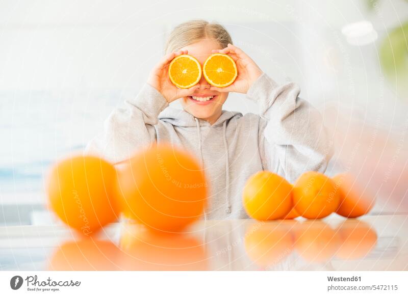 Laughing girl covering her eyes with halves of orange half halved females girls laughing Laughter Orange Oranges cross section cross sections cross-section