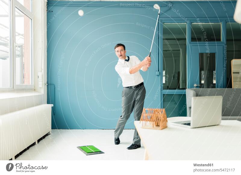 Businessman playing golf in office Business man Businessmen Business men golfing Office Offices business people businesspeople business world business life
