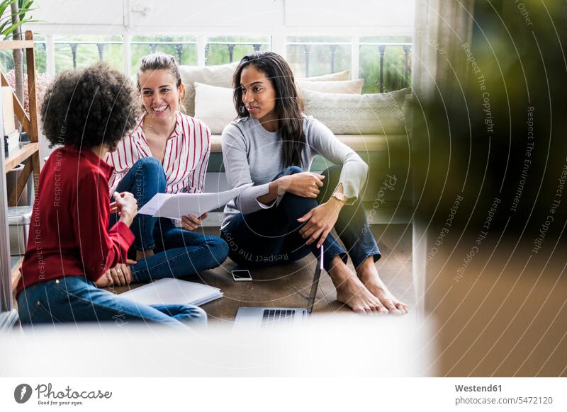 Three women with laptop and documents sitting on the floor at home floors happiness happy woman females Seated Laptop Computers laptops notebook female friends