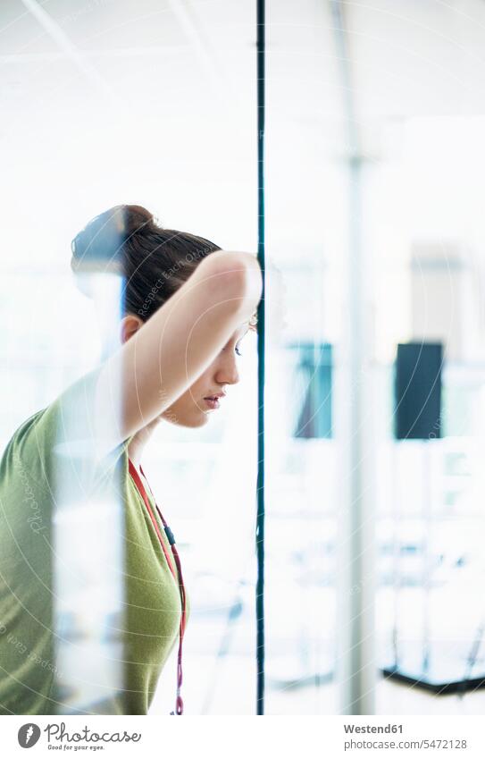 Tired female entrepreneur leaning on glass in office color image colour image indoors indoor shot indoor shots interior interior view Interiors day