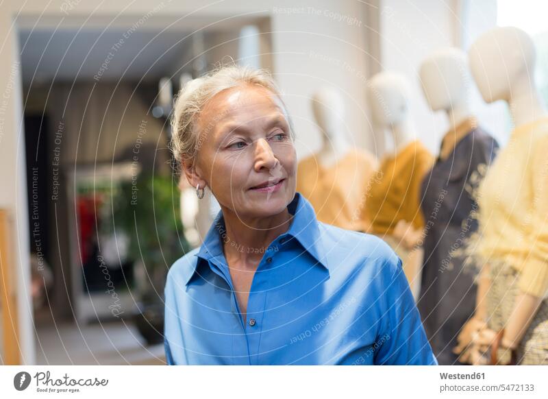 Smiling senior woman in a boutique looking around boutiques females women senior women elder women elder woman old looking round look round look around smiling