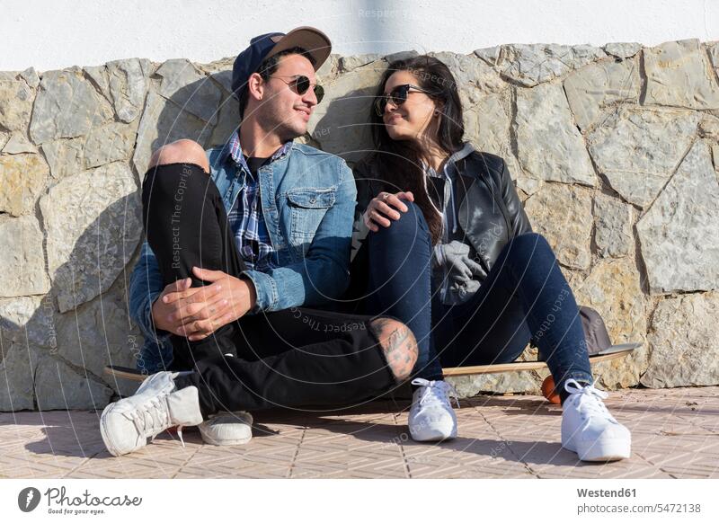 Young couple in love sitting side by side on longboard Eye Glasses Eyeglasses specs spectacles Pair Of Sunglasses sun glasses smile Seated delight enjoyment
