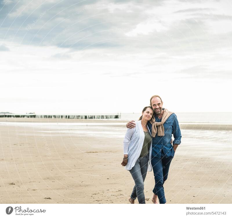Loving couple walking at beach against sky during sunset color image colour image Netherlands Holland The Netherlands Nederland leisure activity