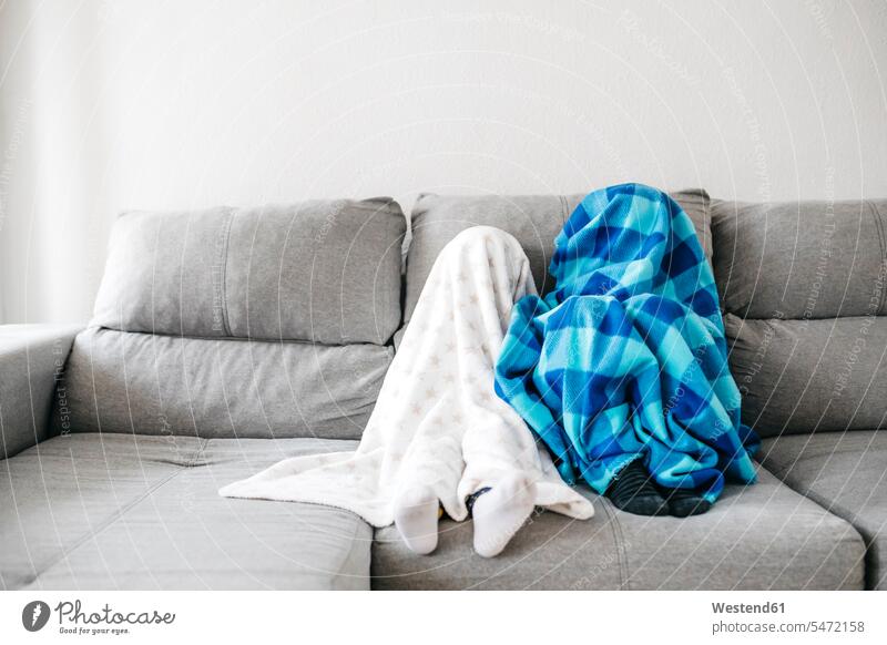 Little girl and her brother sitting side by side on the couch at home hiding under blankets Blankets stockings sock couches settee settees sofa sofas Seated