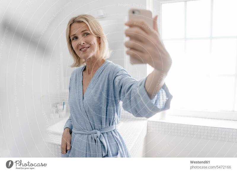 Smiling mature woman taking a selfie in bathroom females women Domestic Bathroom bath room Selfie Selfies confidence confident smiling smile Adults grown-ups