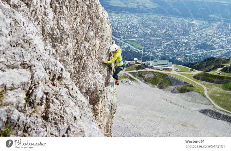 Austria, Innsbruck, Nordkette, woman climbing in rock wall females women rocks rock face escarpment Adults grown-ups grownups adult people persons human being