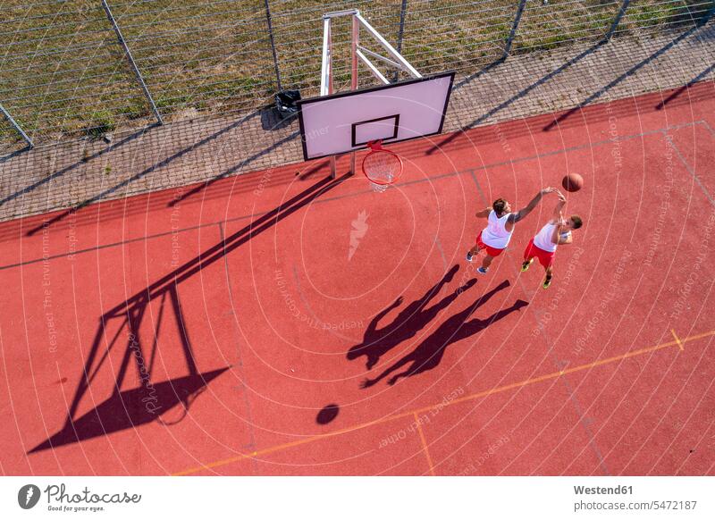 Two young men playing basketball on an outdoor court, aerial view Dedication Engagement dedicated Eager Input eagerness Commitment defence defense defending