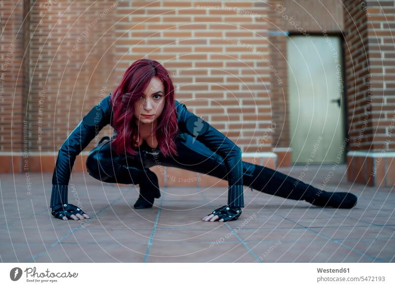 Portrait of redheaded woman wearing black leather catsuit crouching on rooftop gloves colour colours Power Spiritedness Vigor Vigour Vitality Force Strengthy