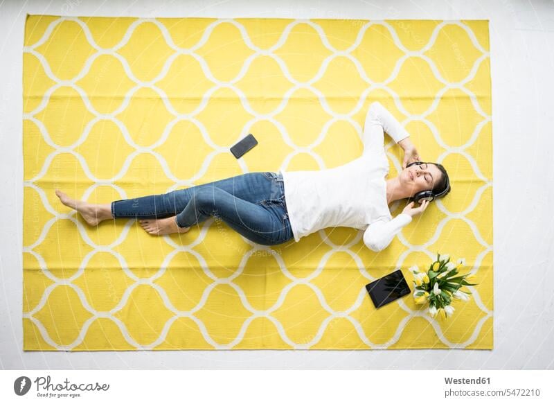 Smiling woman wearing headphones lying on carpet with bunch of tulips Bunch of Flowers Bouquet Flower Bouquet Bouquet of Flowers Flower Bouquets
