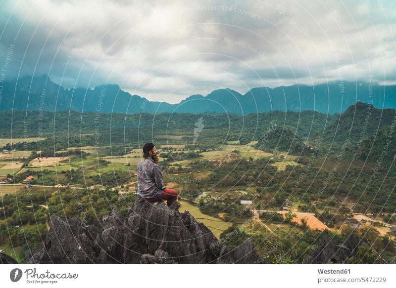 Laos, Vang Vieng, hiker sitting on rock, looking at distance Freedom Liberty free summit mountaintops summits mountain top Looking At View Looking at a view