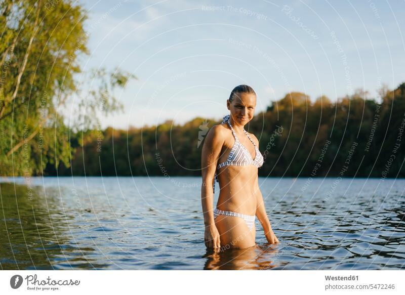 Rear view of woman wearing a bikini at tree trunk at a lake - a Royalty  Free Stock Photo from Photocase