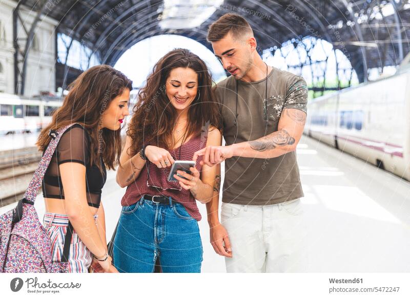 Friends with cell phone on train station platform Railroad Platform station building railway station happiness happy mobile phone mobiles mobile phones