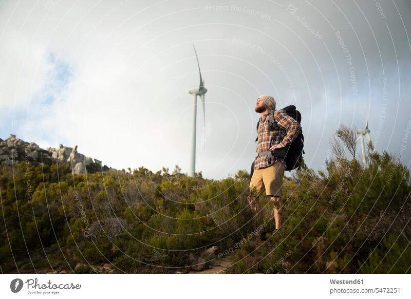 Spain, Andalusia, Tarifa, man on a hiking trip with wind turbine in background hike standing wind turbines hiker wanderers hikers hiking tour walking tour men