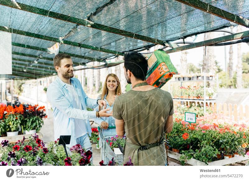 Worker in a garden center handing over soil to customers human human being human beings humans person persons client clientele clients Occupation job jobs