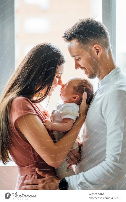 Happy parents playing with baby boy by window at home color image colour image indoors indoor shot indoor shots interior interior view Interiors day
