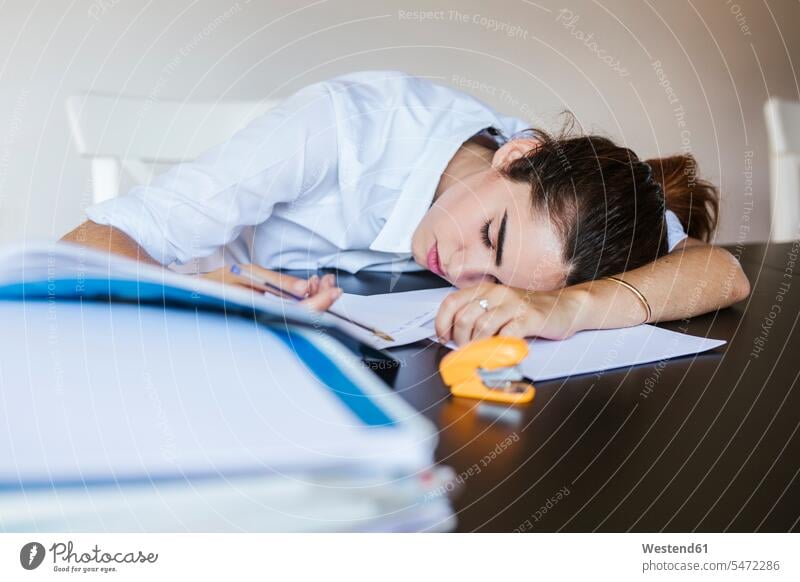 Exhausted female student lying on desk at home with documents Tables desks learn asleep Seated sit study pessimistic despaired Desperation laying down lie