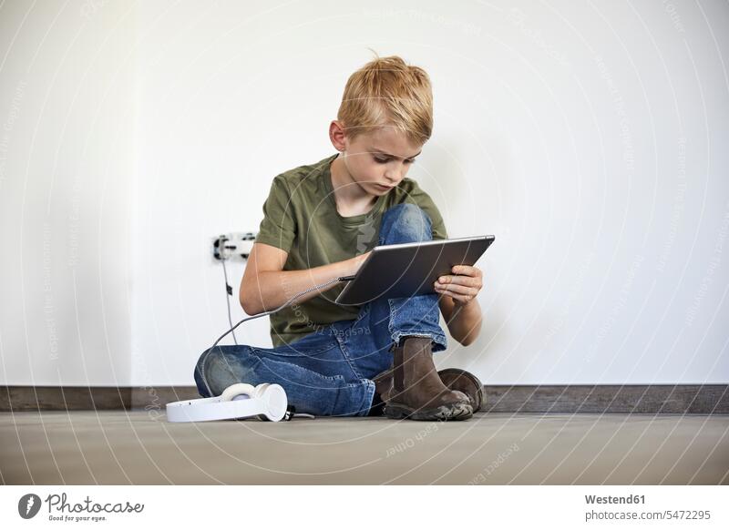 Little boy playing on digital tablet while sitting in new house color image colour image indoors indoor shot indoor shots interior interior view Interiors day