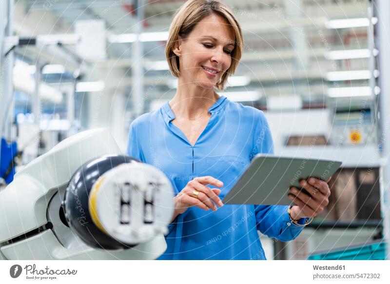 Businesswoman with tablet at assembly robot in a factory human human being human beings humans person persons caucasian appearance caucasian ethnicity european
