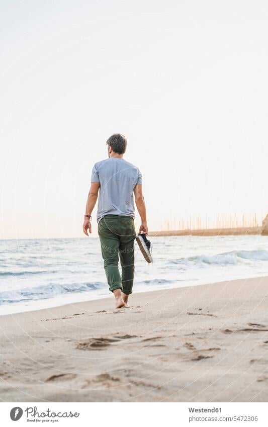 Back view of man walking barefoot on the beach beaches naked feet naked foot Barefeet Bare Feet Bare Foot Barefooted bare-footed going men males Adults