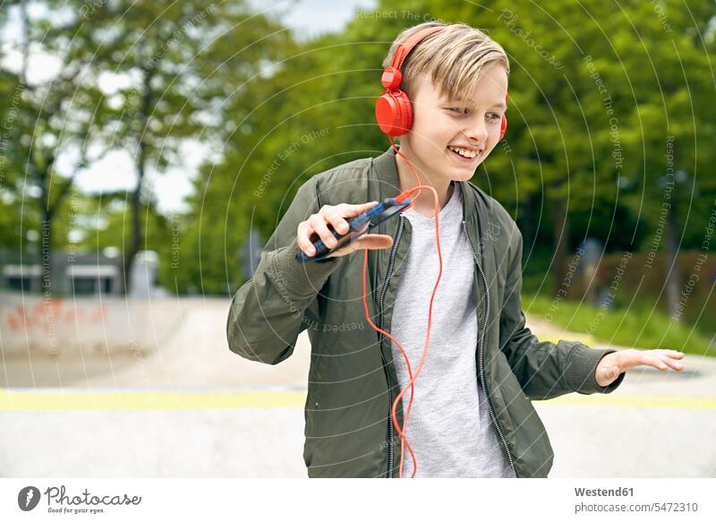 Boy with headphone dancing while listing to music on smartphone headphones headset boy boys males cool attitude composed coolness laid-back hearing smiling