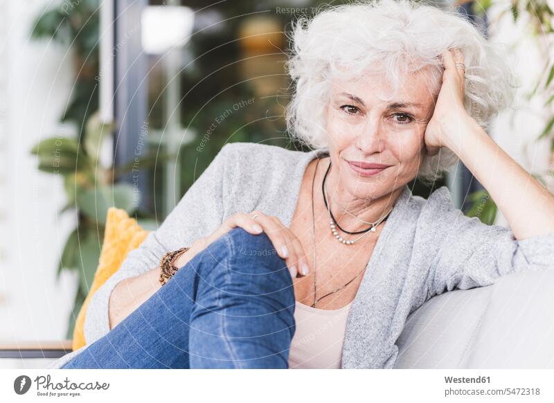 Smiling mature woman with hands in hair looking away while sitting at home color image colour image indoors indoor shot indoor shots interior interior view