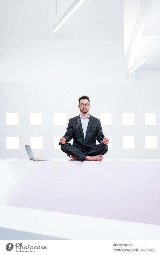Businessman doing yoga in office next to laptop Occupation Work job jobs profession professional occupation business life business world business person