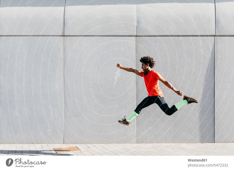 Young man doing jumps with a gray wall in the background human human being human beings humans person persons 1 one person only only one person adult grown-up
