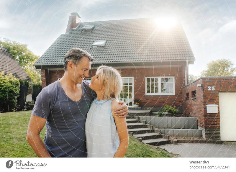 Smiling mature couple embracing in garden of their home smiling smile house houses twosomes partnership couples gardens domestic garden embrace Embracement hug