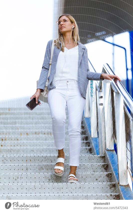 Young businesswoman walking down stairs and holding her mobile phone business life business world business person businesspeople business woman business women
