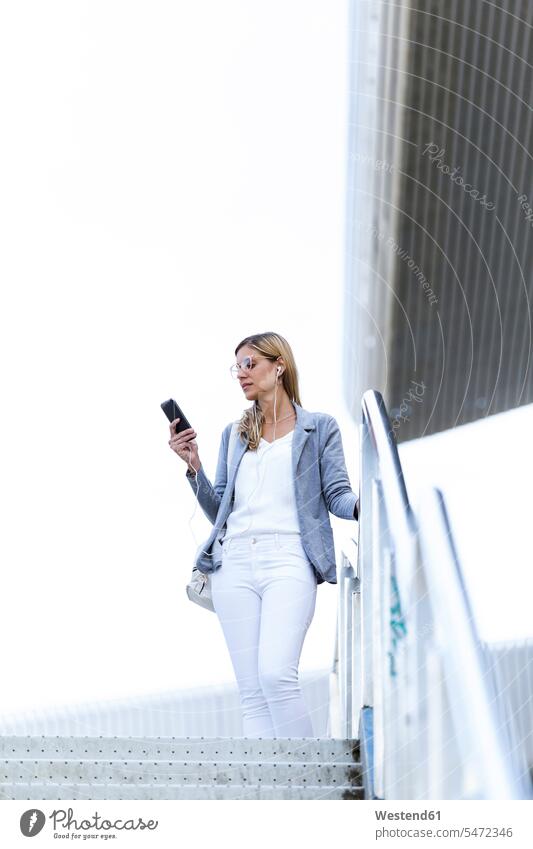 Young businesswoman listening to music with mobile phone on stairs business life business world business person businesspeople business woman business women