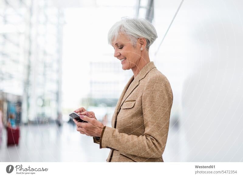 Smiling senior businesswoman using cell phone businesswomen business woman business women females senior women elder women elder woman old senior woman smiling