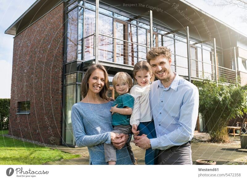 Portrait of smiling family in front of their home house houses smile portrait portraits families building buildings built structure built structures people