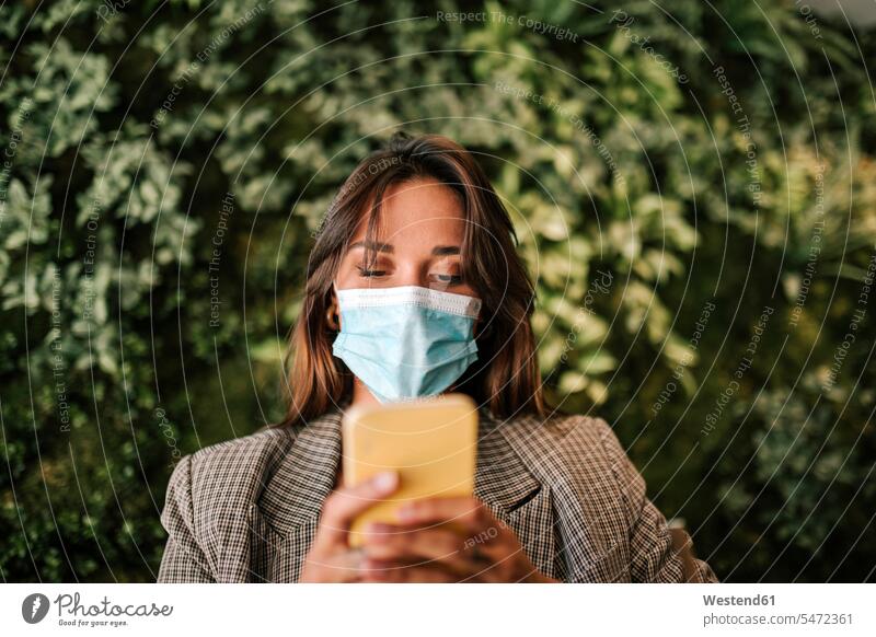 Woman using smart phone wearing protective face mask while sitting in cafe color image colour image indoors indoor shot indoor shots interior interior view